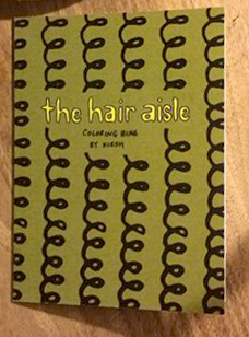 photo of The Hair Aisle Coloring Zine: green background with curls in vertical stripes, yellow title